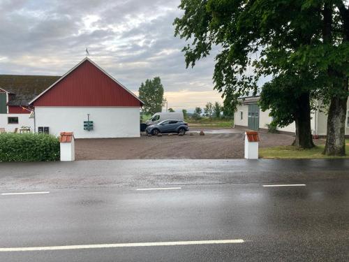 een auto geparkeerd naast een wit gebouw met een rood dak bij Fin lägenhet på Bjäre med nära till natur och nöje in Båstad