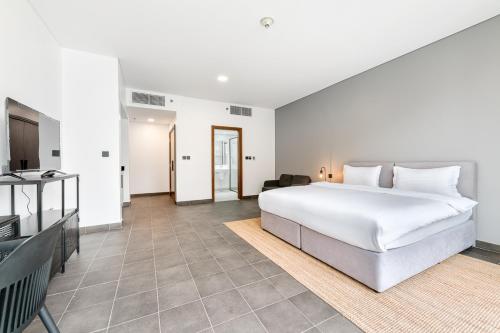 a bedroom with a large white bed and a television at Emirates Sports Hotel, Dubai Sports City in Dubai
