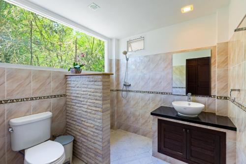 ラワイビーチにある3BR Villa Barnabé with Lush Gardenのバスルーム(トイレ、洗面台付)、窓が備わります。