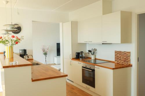 a kitchen with white cabinets and a counter top at Penthouse - Amazing views & hygge in Copenhagen