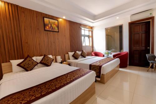 een hotelkamer met 2 bedden en een rode stoel bij Airport Saigon Hotel - Gần ẩm thực đêm chợ Phạm Văn Hai in Ho Chi Minh-stad