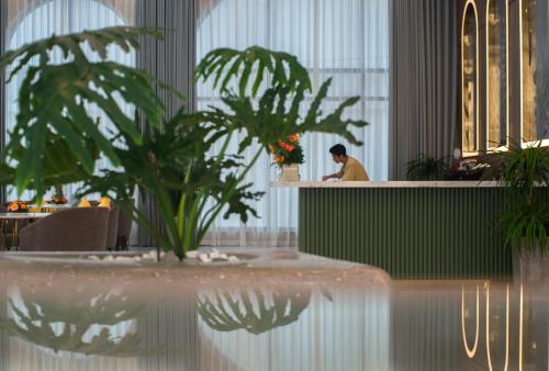 a man sitting at a counter in a room with plants at Grand Tourane Nha Trang Hotel in Nha Trang