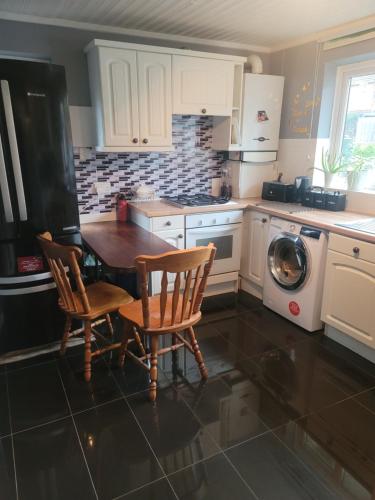 een keuken met een tafel en stoelen en een wasmachine bij The Bungalow in Kent