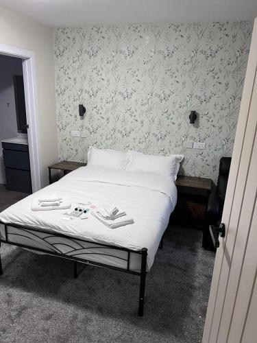 um quarto com uma cama com lençóis brancos e papel de parede floral em Woolaway em Taunton