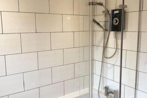 a shower in a bathroom with white tiled walls at Plum Tree Corner in Chapel Saint Leonards
