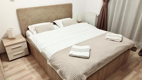 a bedroom with a large bed with towels on it at Luxury Mountain View Apartment in Braşov