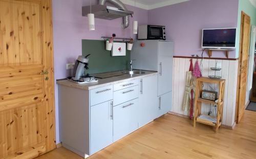 Una cocina con gabinetes blancos y un refrigerador. en Lütt Logis in Grödersby, en Grödersby