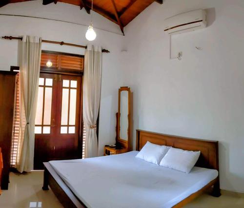 um quarto com uma cama branca e uma janela em Serendip Villa Holiday Home Talalla Sri Lanka em Talalla South