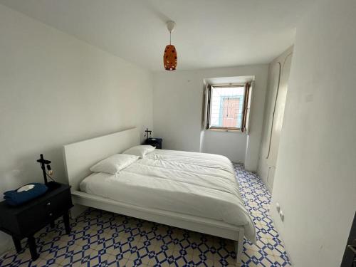 a white bedroom with a bed and a window at Puskin Suite in Sines
