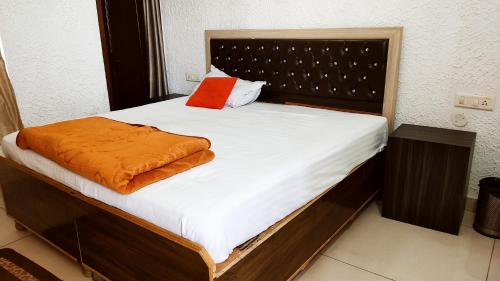 ein Bett mit einer orangefarbenen Decke darüber in der Unterkunft WHITE HOUSE Luxury Rooms - Loved by Travellers, Couples, Corporates in Jalandhar