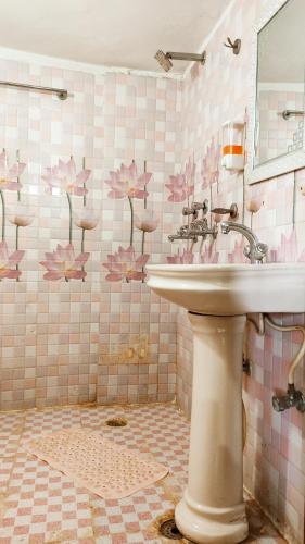 a bathroom with a sink and pink flowers on the wall at WHITE HOUSE Luxury Rooms - Loved by Travellers, Couples, Corporates in Jalandhar