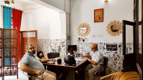 three men sitting at a table in a room at WHITE HOUSE Luxury Rooms - Loved by Travellers, Couples, Corporates in Jalandhar