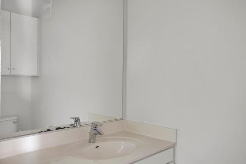 Un baño blanco con lavabo y espejo. en Somerville 1BR w wd nr Assembly T BOS-755, en Somerville