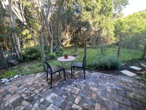 a patio with two chairs and a table in a yard at The Wood Owl Nature's Valley in Natureʼs Valley