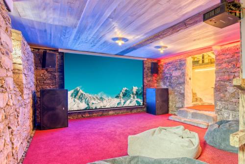 um quarto com um grande ecrã numa parede de pedra em Jup - a luxury boutique chalet em Warth