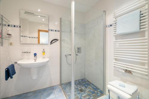 a white bathroom with a shower and a sink at Villa Dünenblick 02 in Zingst