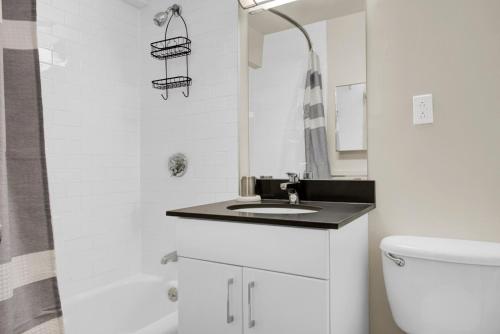a white bathroom with a sink and a toilet at Spacious Beacon Hill 1BR wViews Gym BOS-498 in Boston