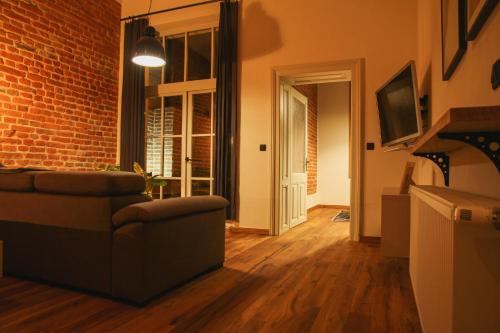 Grossmann Apartment في ليوتومير: غرفة معيشة مع أريكة وجدار من الطوب