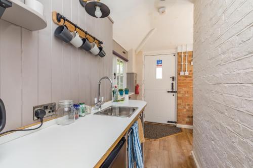 cocina con fregadero y pared de ladrillo en Old Mill Lodge by Huluki Sussex Stays en Hurstpierpoint