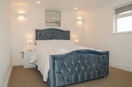 a bedroom with a large bed with a blue headboard at Luxury 5 Star London Apartment - Parking, Garden, nr Greater London Metro Stations in Forest Hill