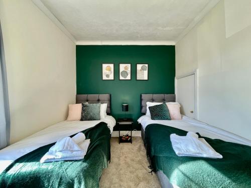 Dos camas en una habitación con paredes verdes. en Emerald Lodge Central 3 Bed Parking WI-FI Garden close to centre, en Chelmsford