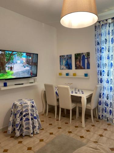 ein Esszimmer mit einem Tisch, Stühlen und einem TV in der Unterkunft villa martina apartament in Ischia