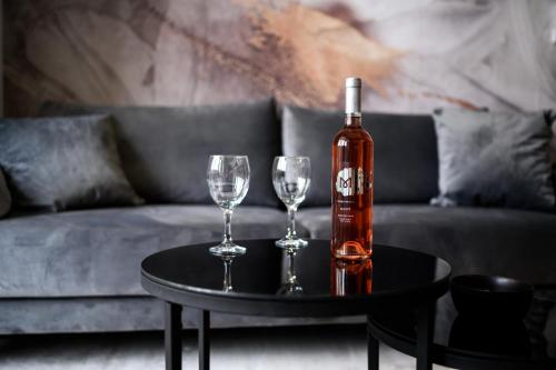 a bottle of wine and two wine glasses on a table at Apartman Olimp in Metković