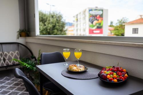 a table with two glasses of wine and a bowl of fruit at Apartman Olimp in Metković