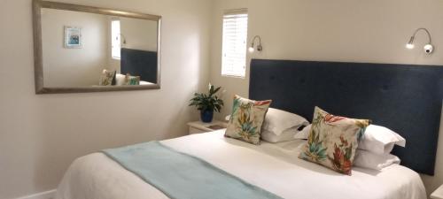 a bedroom with a large white bed with a mirror at C-Vista in Stilbaai-Wes