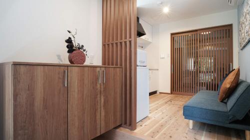 a living room with a wooden cabinet and a blue chair at 伏見稲荷平田町 in Kyoto