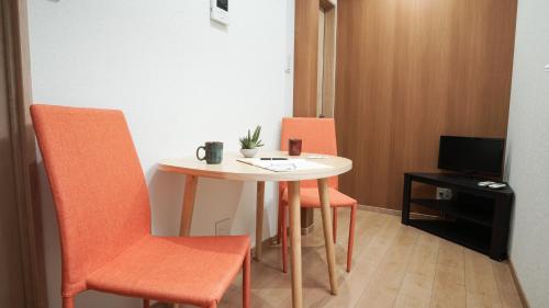 a small table with orange chairs in a room at 伏見稲荷平田町 in Kyoto