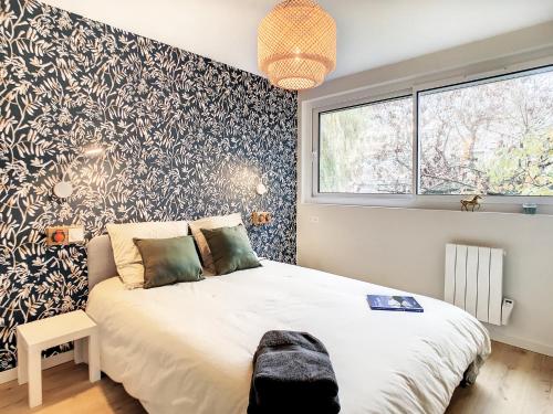a bedroom with a large white bed with a black and white wallpaper at Appartement Ancely tout neuf déco aéro - parking gratuit - Proche Blagnac in Toulouse