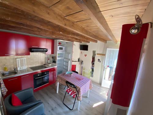- une cuisine avec des placards rouges et une table dans une pièce dans l'établissement Le vieux logis, à Étretat