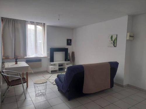 a living room with a couch and a table and a tv at Fresnay-sur-Sarthe: joli appartement au calme. in Fresnay-sur-Sarthe