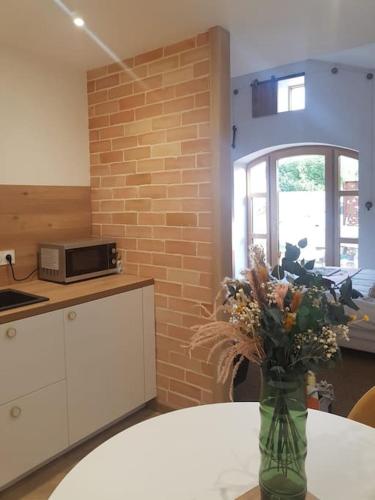 un vase de fleurs assis sur une table dans une cuisine dans l'établissement Domaine de la Gasse - gite et chambre d'hôte, à Sainte-Cécile