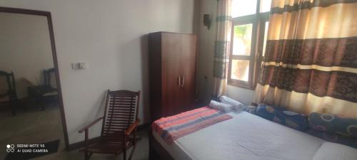 a bedroom with a bed and a chair and a window at Trellis Homes in Colombo