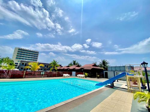 une grande piscine avec un toboggan bleu dans l'établissement Langgura Baron Resort, à Pantai Cenang