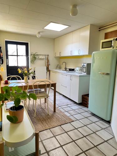 a kitchen with a table and a green refrigerator at Askes Oase Guest Apartment in Fjællebroen