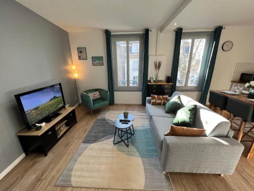 a living room with a couch and a flat screen tv at Charmant appartement T2 cosy climatisé in Brive-la-Gaillarde