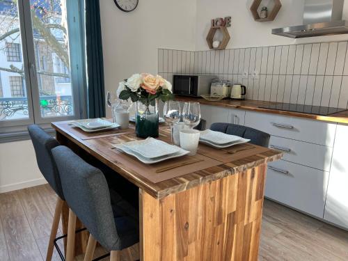 una cocina con una mesa de madera y un jarrón de flores en Charmant appartement T2 cosy climatisé en Brive-la-Gaillarde
