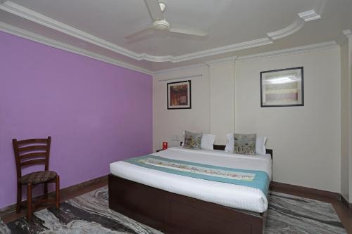 a bedroom with a bed with purple walls and a chair at OYO Hotel Bliss Executive Near Sant Tukaram Nagar Metro Station in Chinchwad