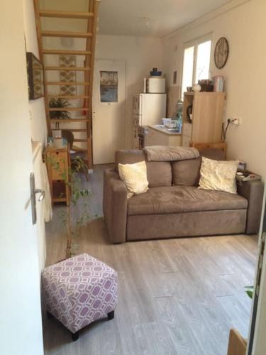 uma sala de estar com um sofá e um repousa-pés em F2 en centre-ville Chevreuse em Chevreuse