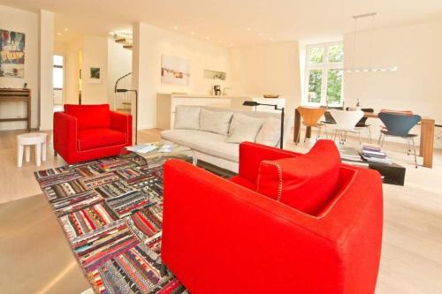 uma sala de estar com duas cadeiras vermelhas e um sofá em Villa Hintze App 13 em Heringsdorf