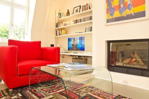 uma sala de estar com uma cadeira vermelha e uma lareira em Villa Hintze App 13 em Heringsdorf