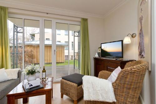 een woonkamer met een bank, een tafel en een televisie bij Villa Louise App 4 in Ahlbeck