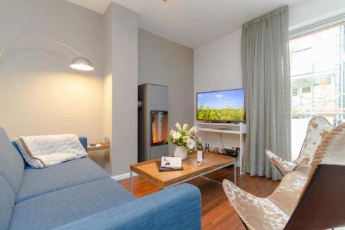ein Wohnzimmer mit einem blauen Sofa und einem Fernseher in der Unterkunft Villa Limora, App. 04 in Heringsdorf