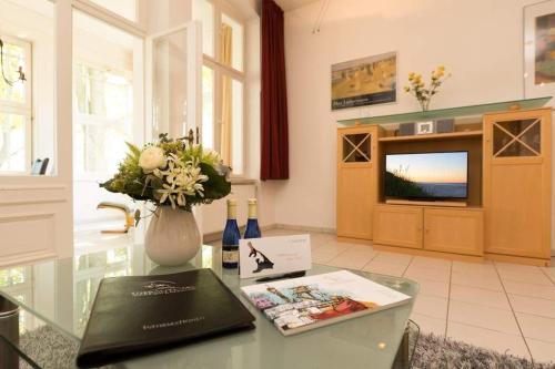 una sala de estar con una mesa con un jarrón de flores en Villa Medici Heringsdorf App 07, en Bansin