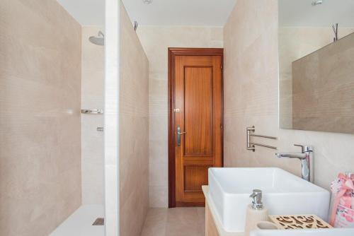 y baño con lavabo blanco y ducha. en Apartamentos La Cortina en Cangas de Onís