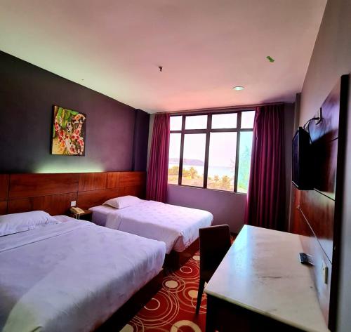 a hotel room with two beds and a window at Langgura Baron Resort in Pantai Cenang