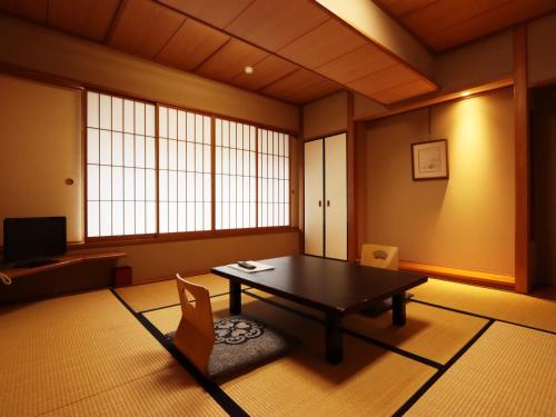 a living room with a table and chairs and windows at Nishiki-no-Yu Jimotoya in Matsumoto